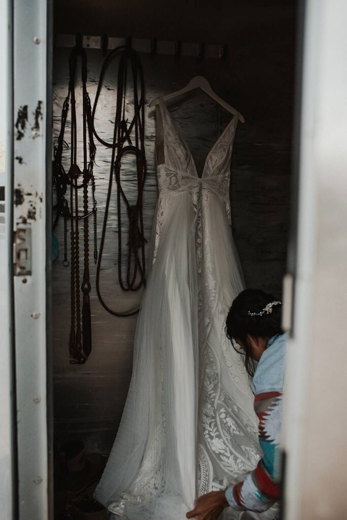 Bride getting her dress ready in a tack room 