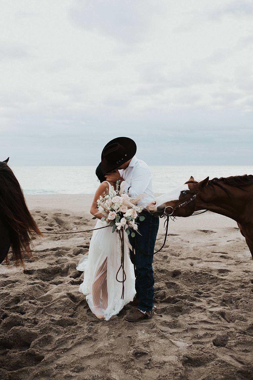 Bride and groom first kiss on Florida beach during their elopement with their horses