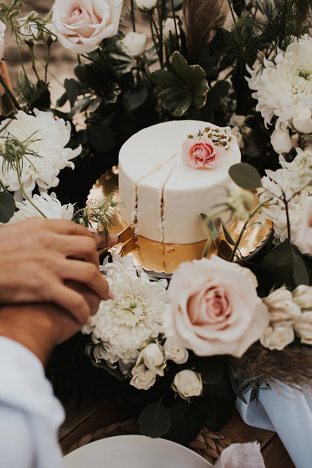 Bride and groom cutting their cake in floral cake meadow on the beach after their Florida elopement