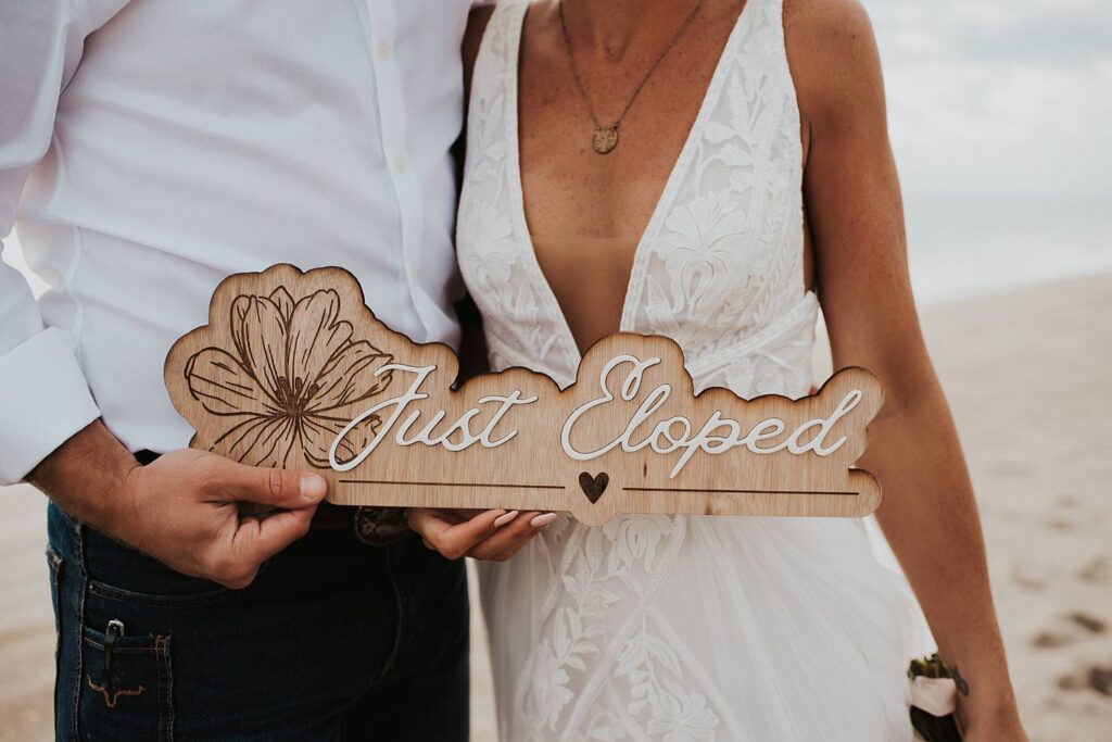 Wood and acrylic just eloped sign being held by bride and groom