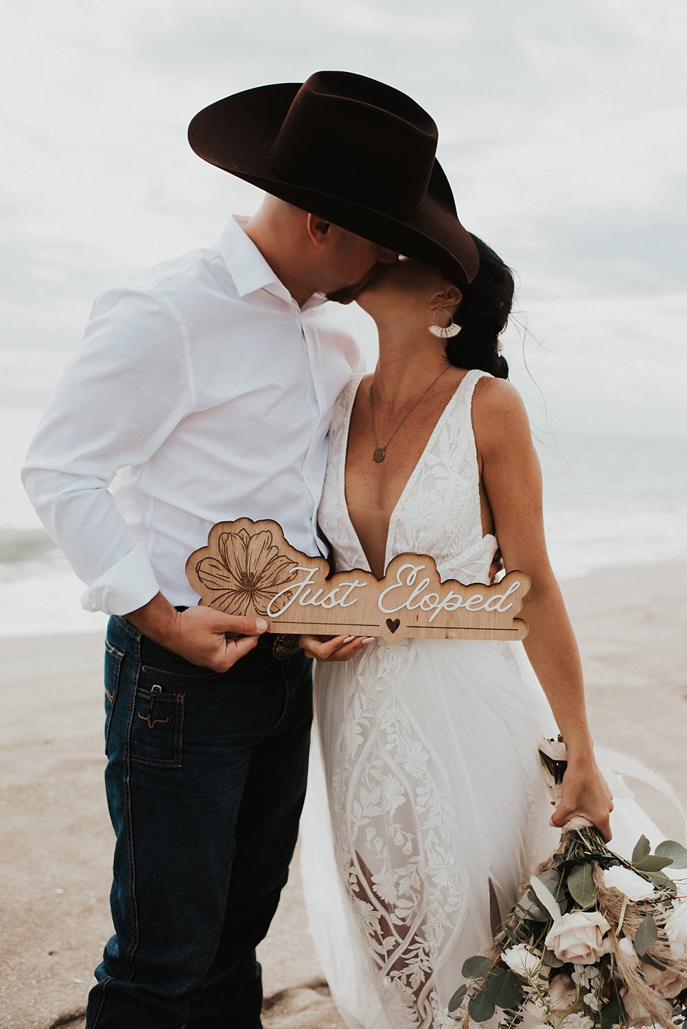 Wood and acrylic just eloped sign being held by bride and groom