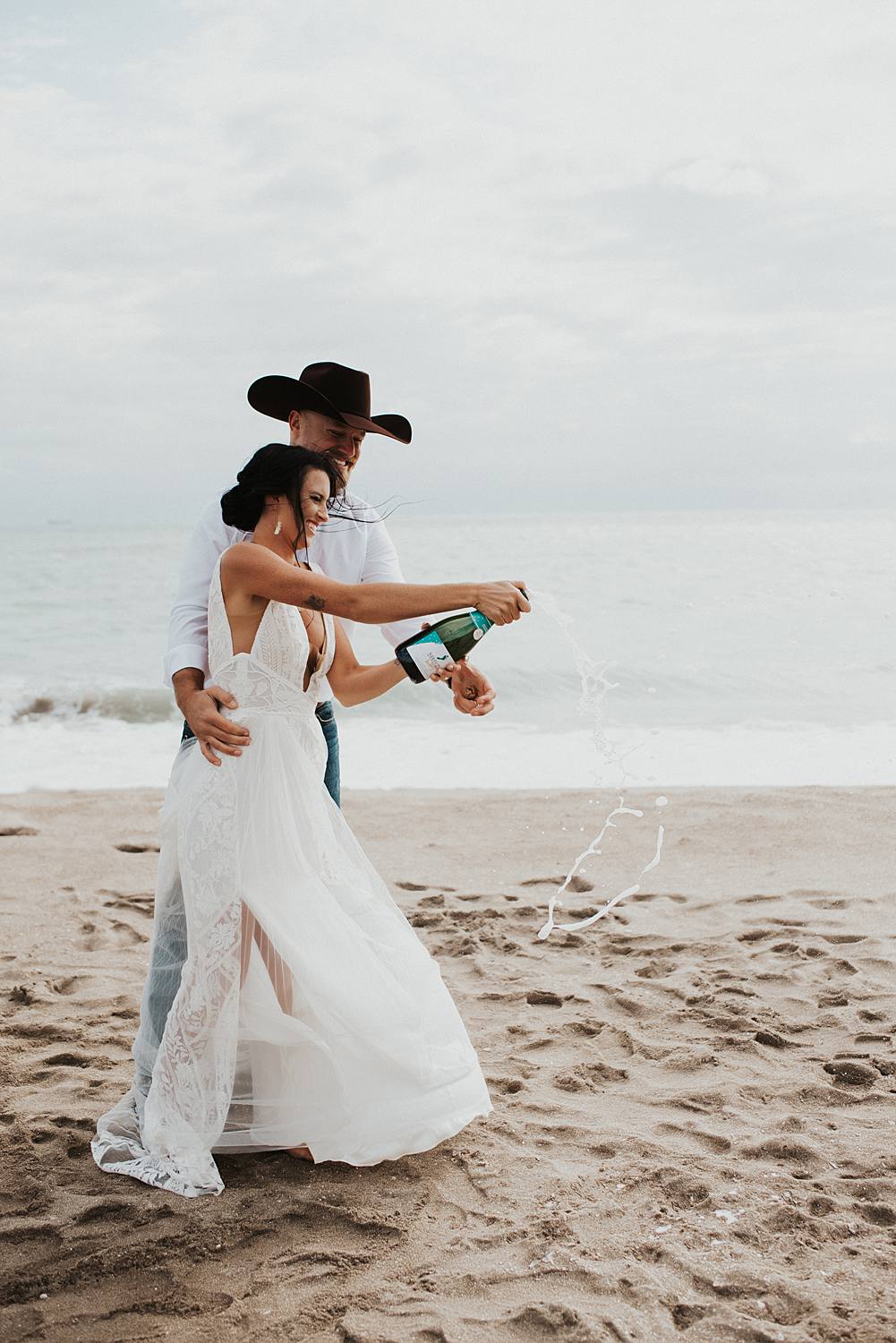 Bride and groom popping champagne on the beach after their Florida elopement