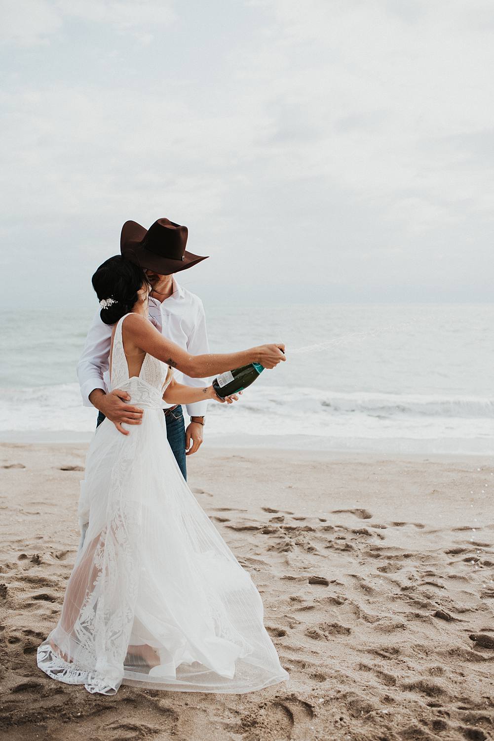 Bride and groom popping champagne on the beach after their Florida elopement