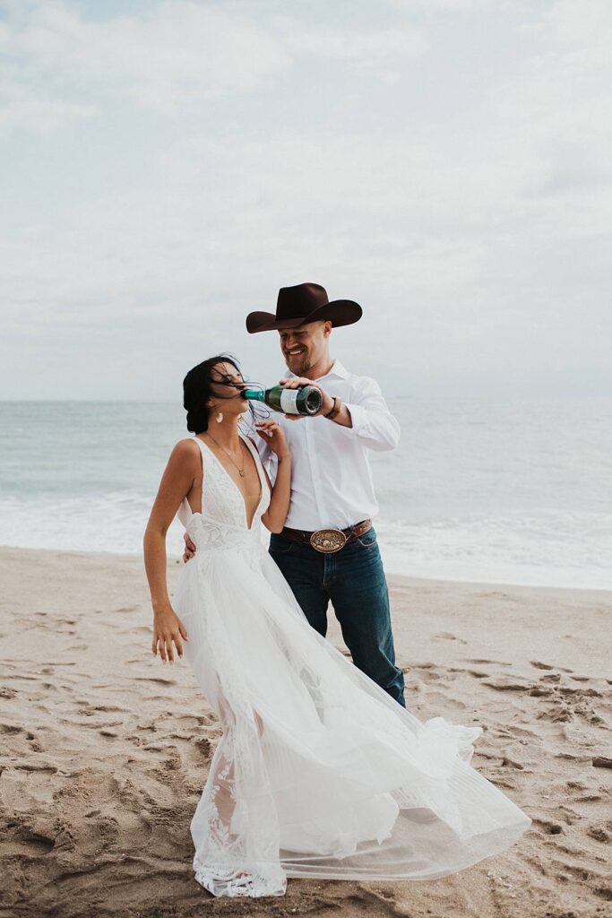 Bride and groom popping champagne on the beach after their Florida elopement