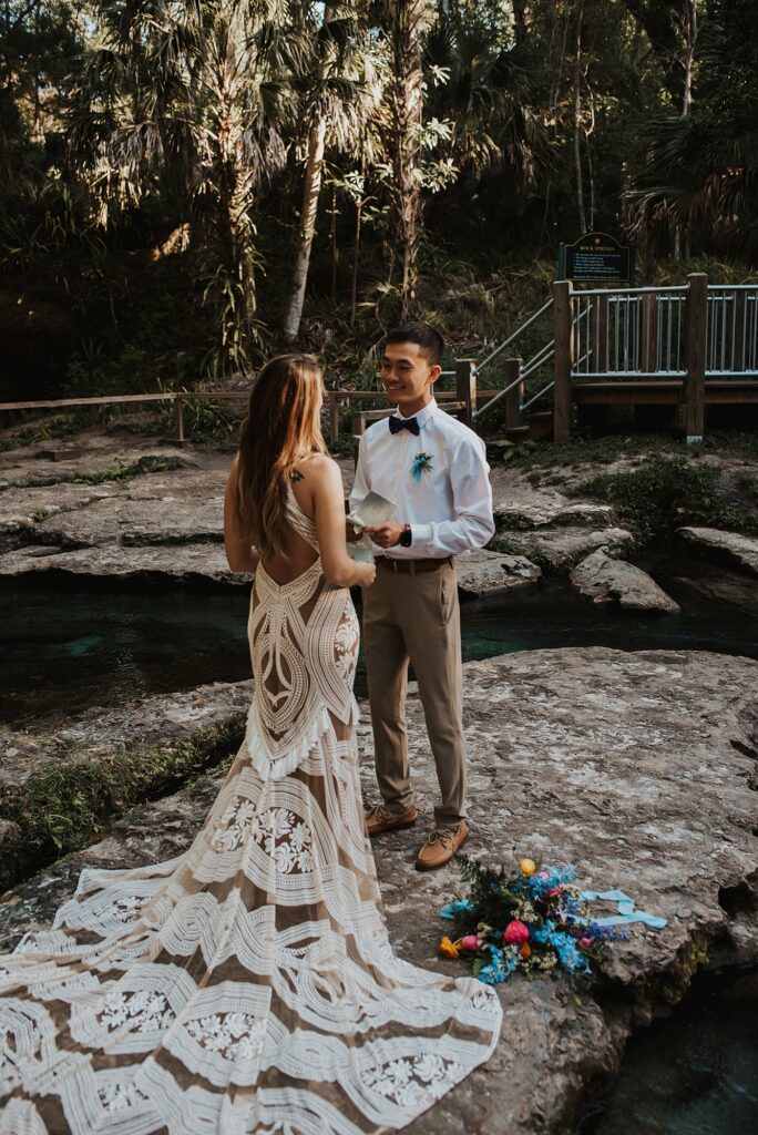 Bride and groom exchanging vows on rock surrounded by crystal clear blue water in Kelly Park Rock Spring 