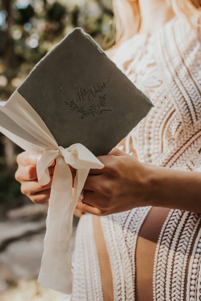 Paper and ribbon vow book in brides hands