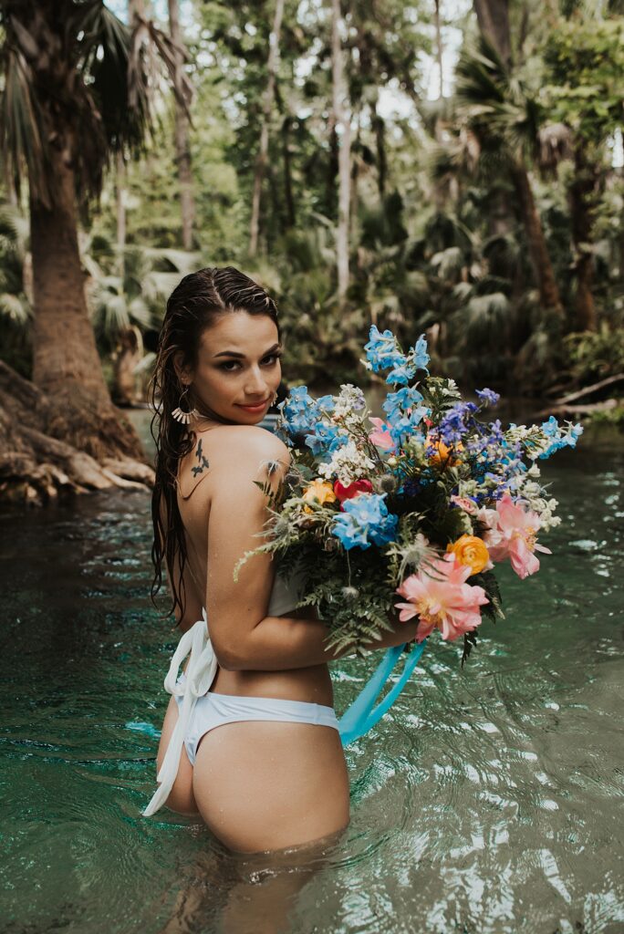Bride in bikini getting into water at King's Landing with her spring-inspired bouquet 