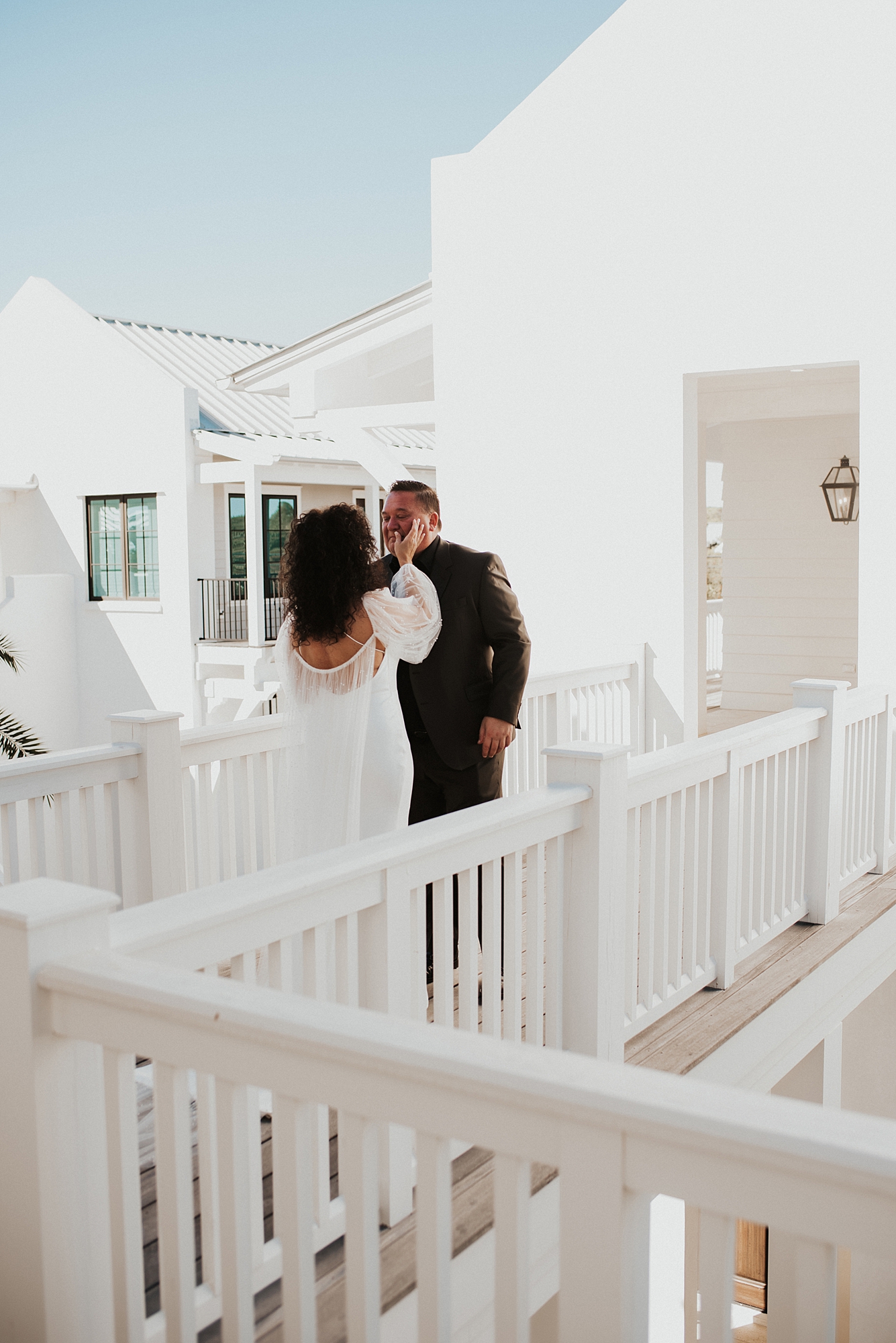 Bride and groom sharing a moment during first look as bride wipes away tear from groom's face