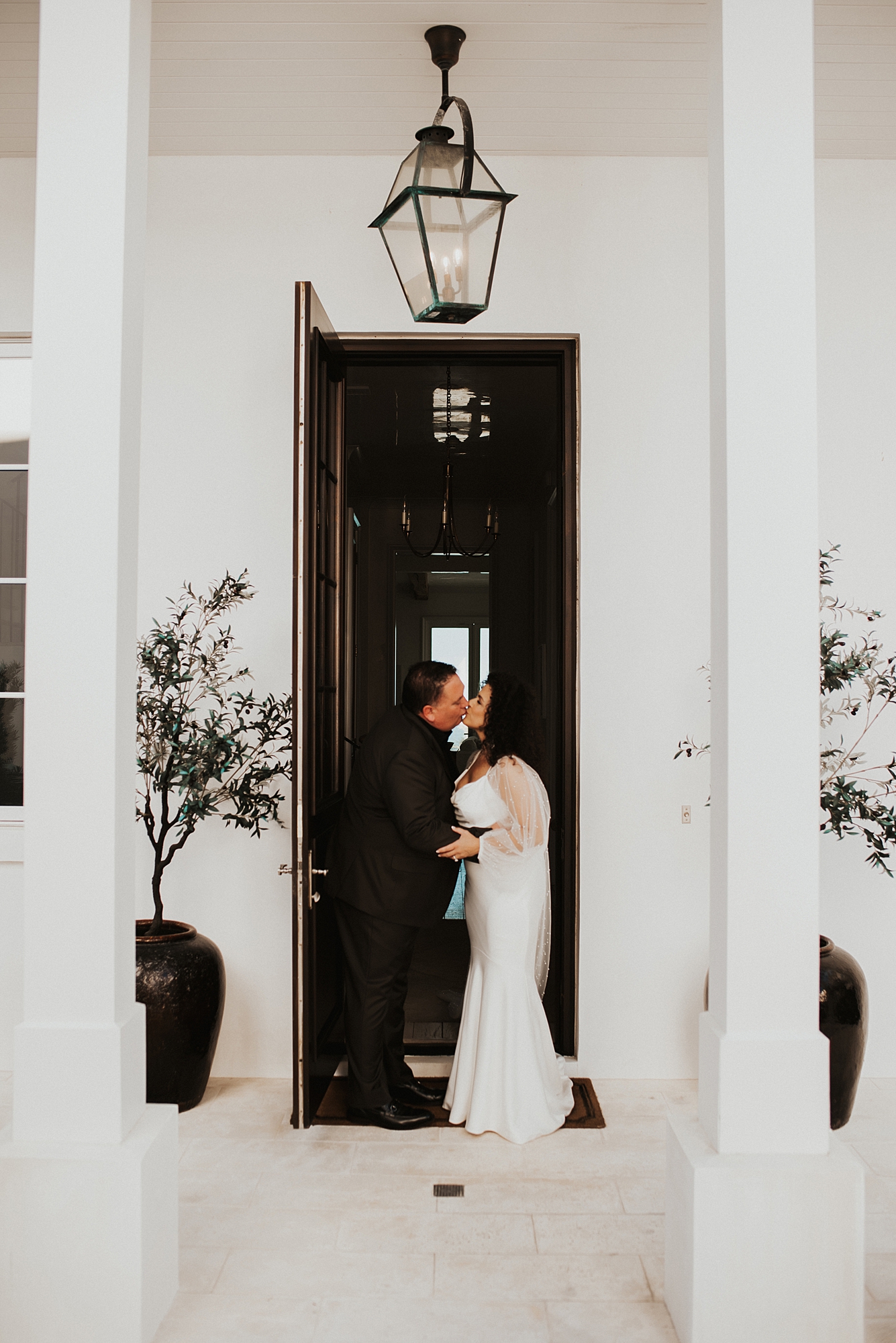 Bride and groom sharing a kissing in entry way