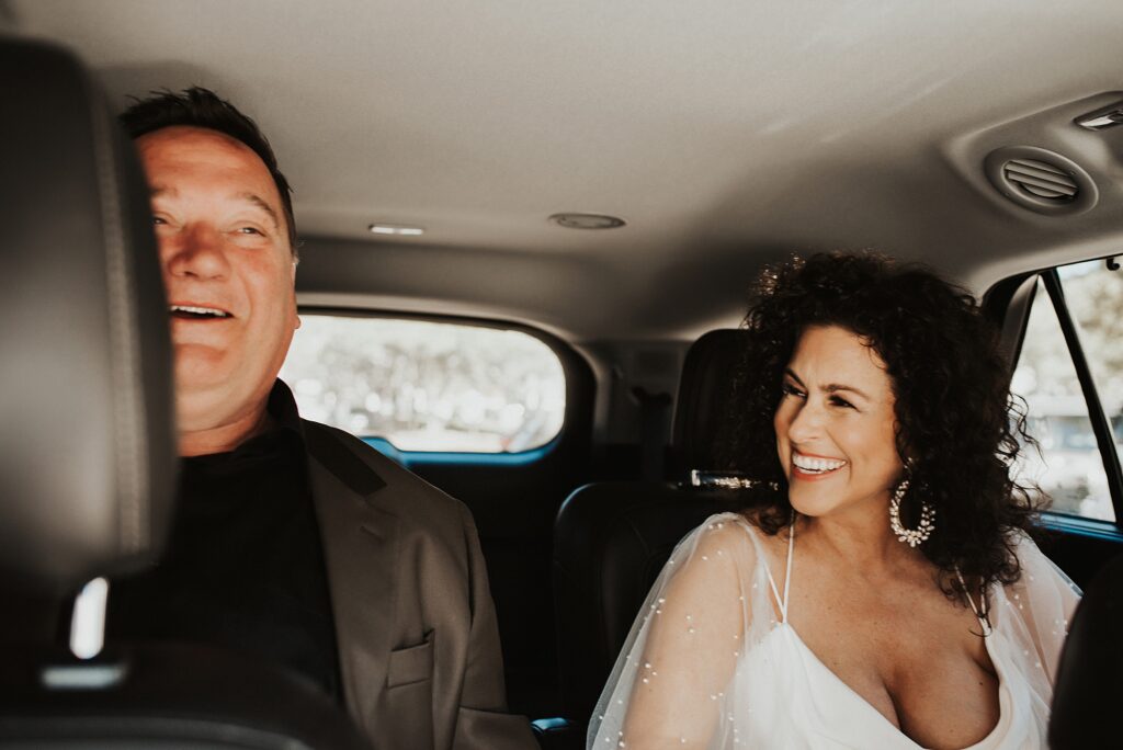 Bride smiling at groom inside of a car