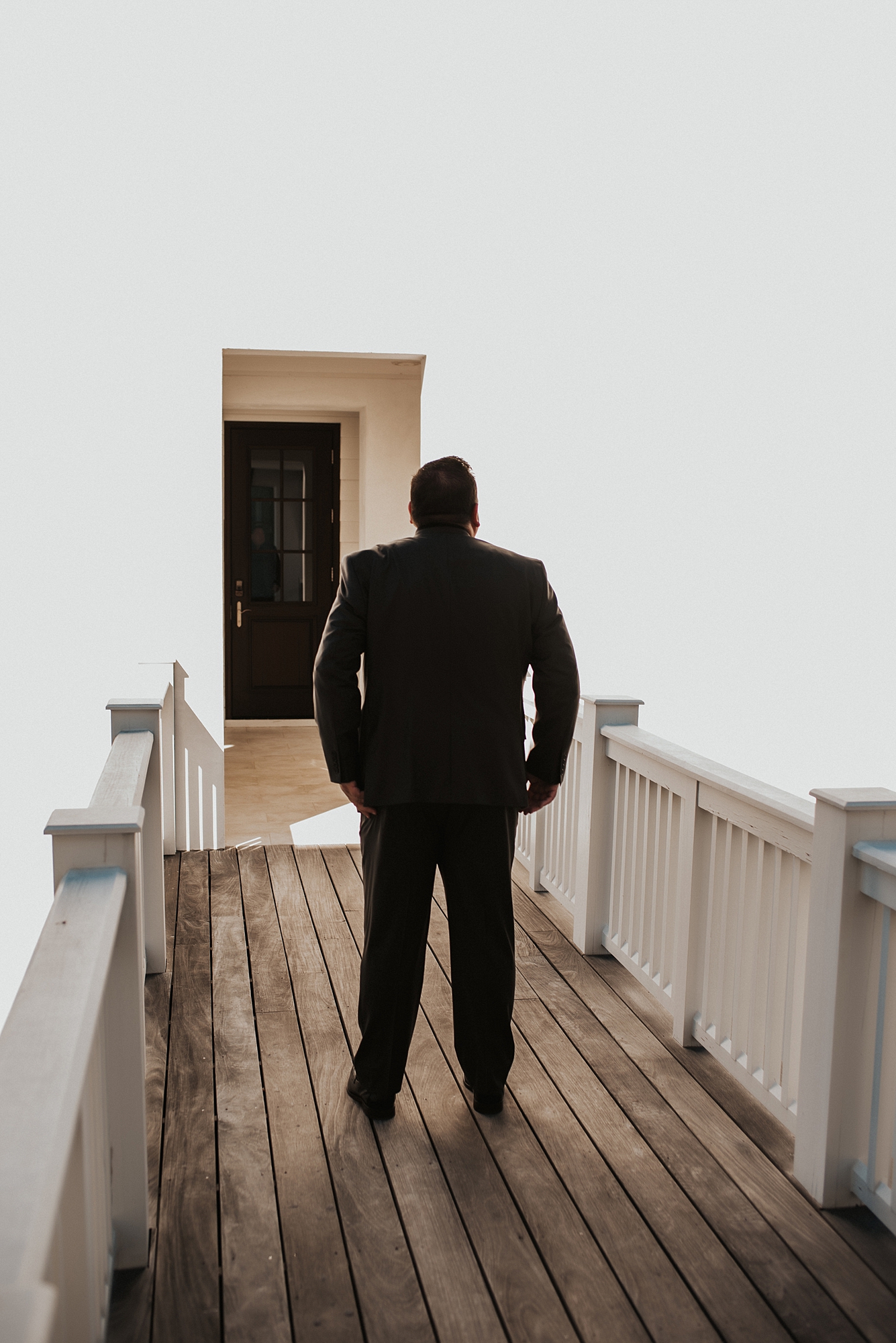 Groom patiently waiting on porch for first look with bride